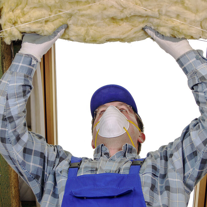 Worker thermally insulating a house attic using mineral wool