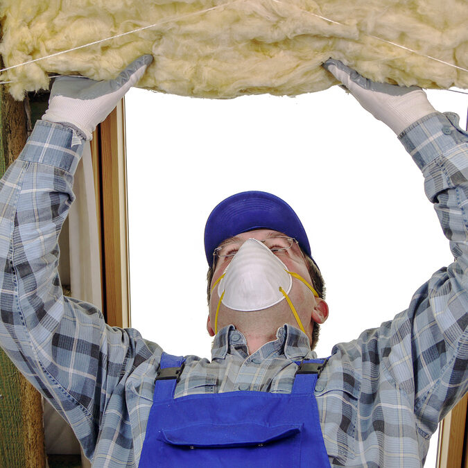 Worker thermally insulating a house attic using mineral wool Worker thermally insulating a house attic using mineral wool